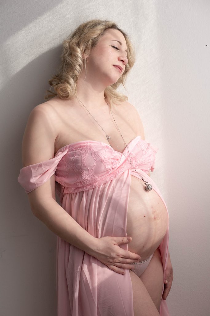 prepararsi al servizio fotografico di maternità donna incinta mentre posa in studio fotografico per un servizio fotografico di maternity